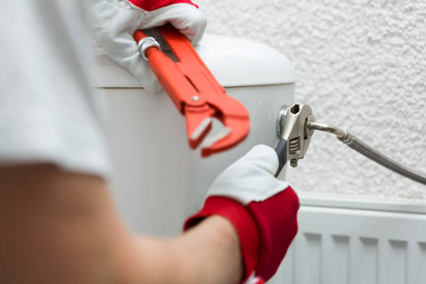 plumber installing pipe to water closet with wrench